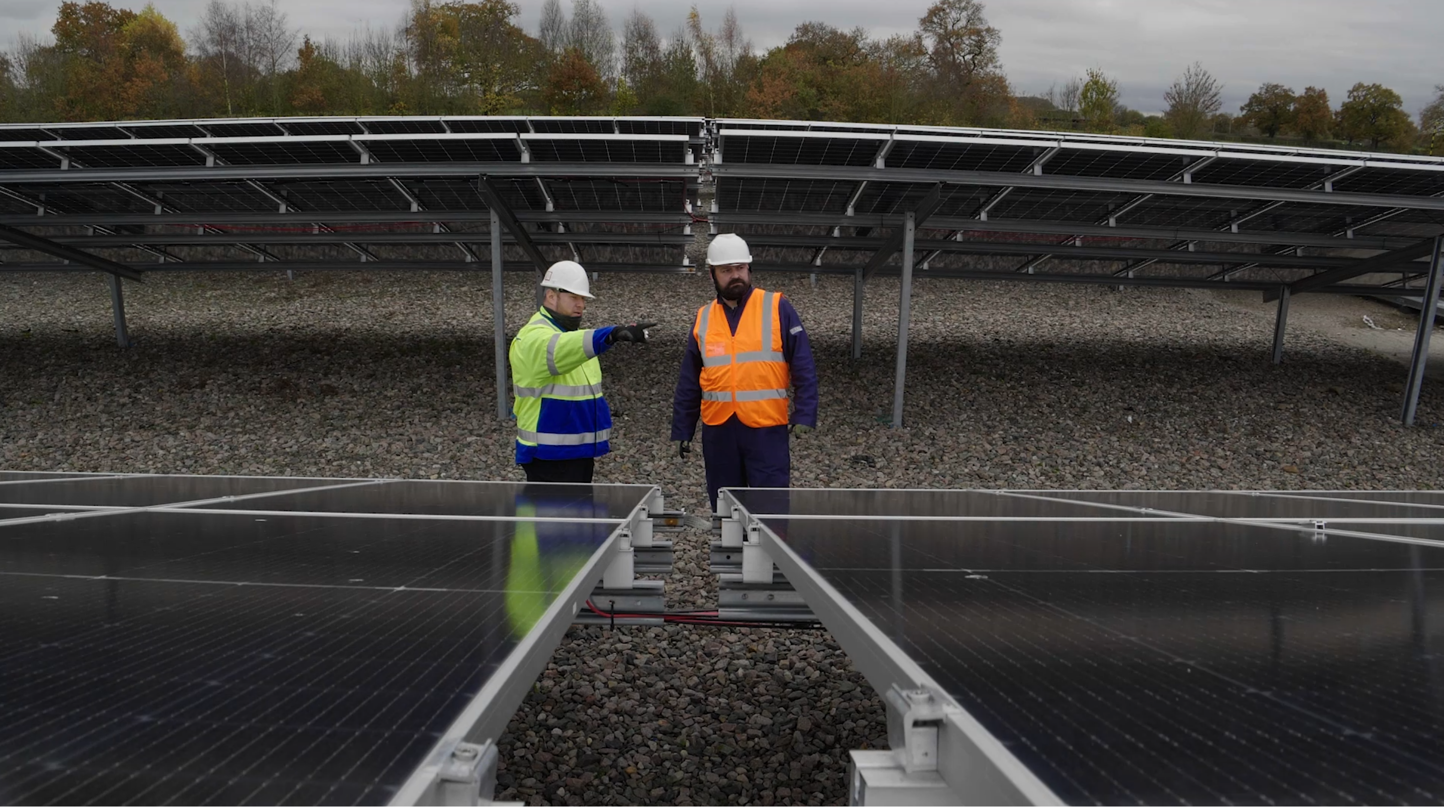 two engineers looking at a solar farm in a field providing asset management