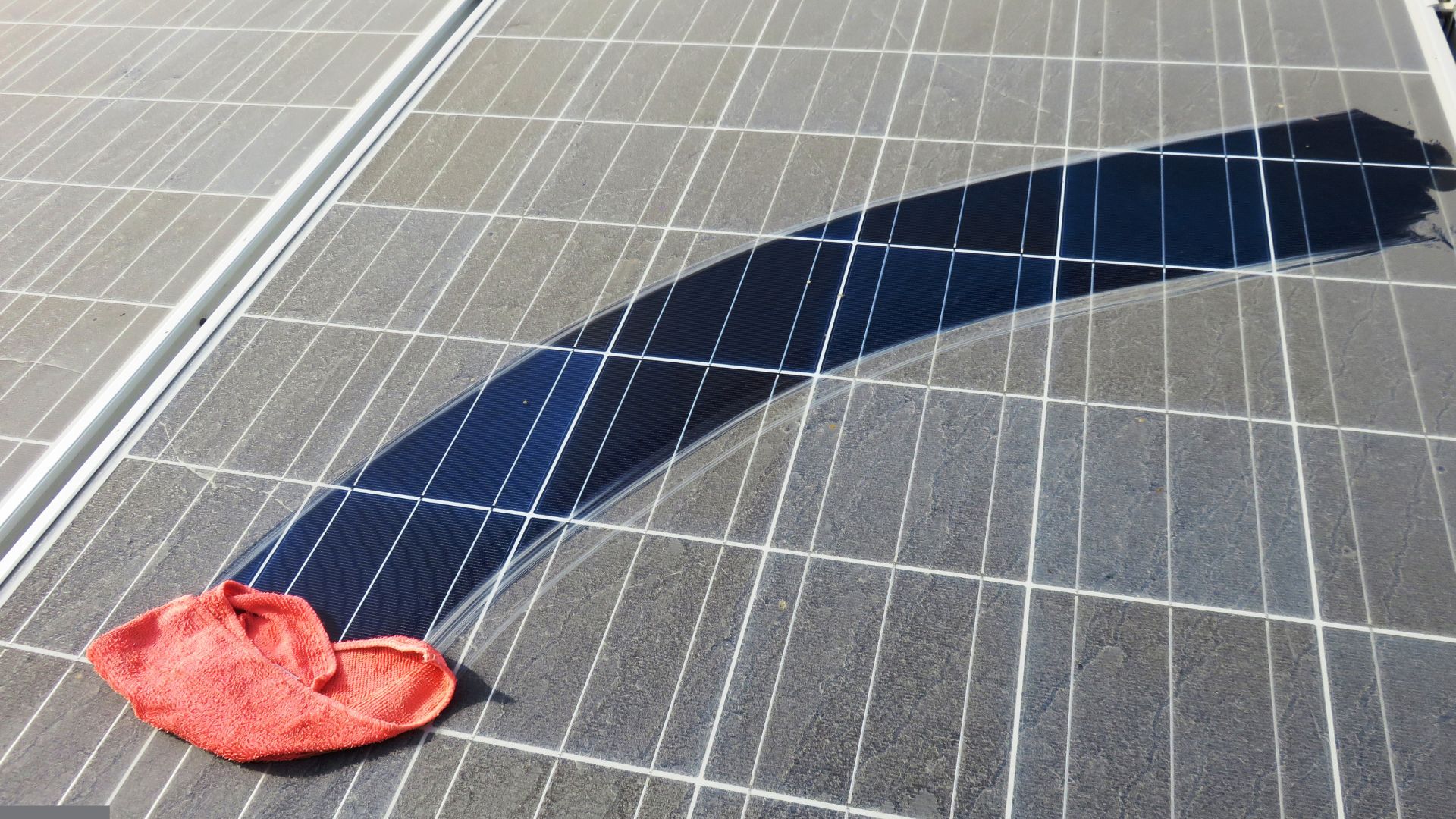Detail of a red cleaning cloth left on photovoltaic solar panels after cleaning.